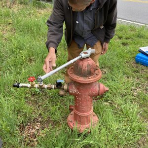 Water system operator using a hydrant sampler device to perform calculated flush times from a water hydrant before distribution system sampling