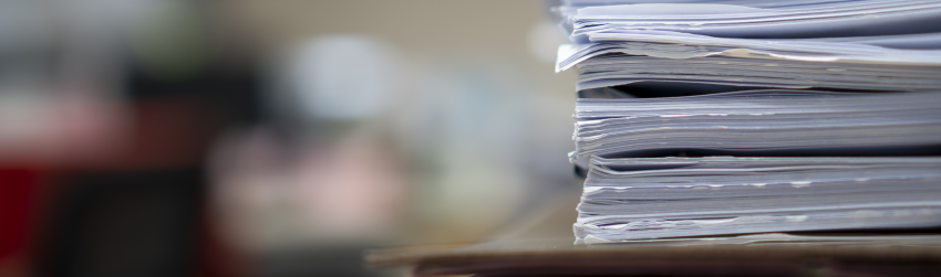Papers stacked on the side of a desk