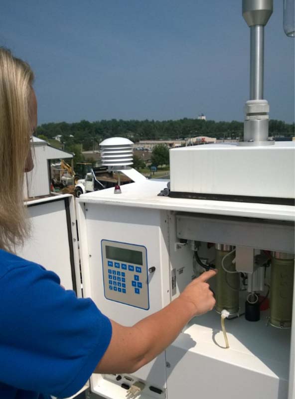 An air monitoring specialist works with a PM2.5 manual sampler.